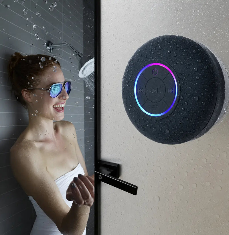 Caixa de som Bluetooth portátil com ventosa e resistência à água IPX4 instalada no box do banheiro, ideal para ouvir música durante o banho e em ambientes externos.