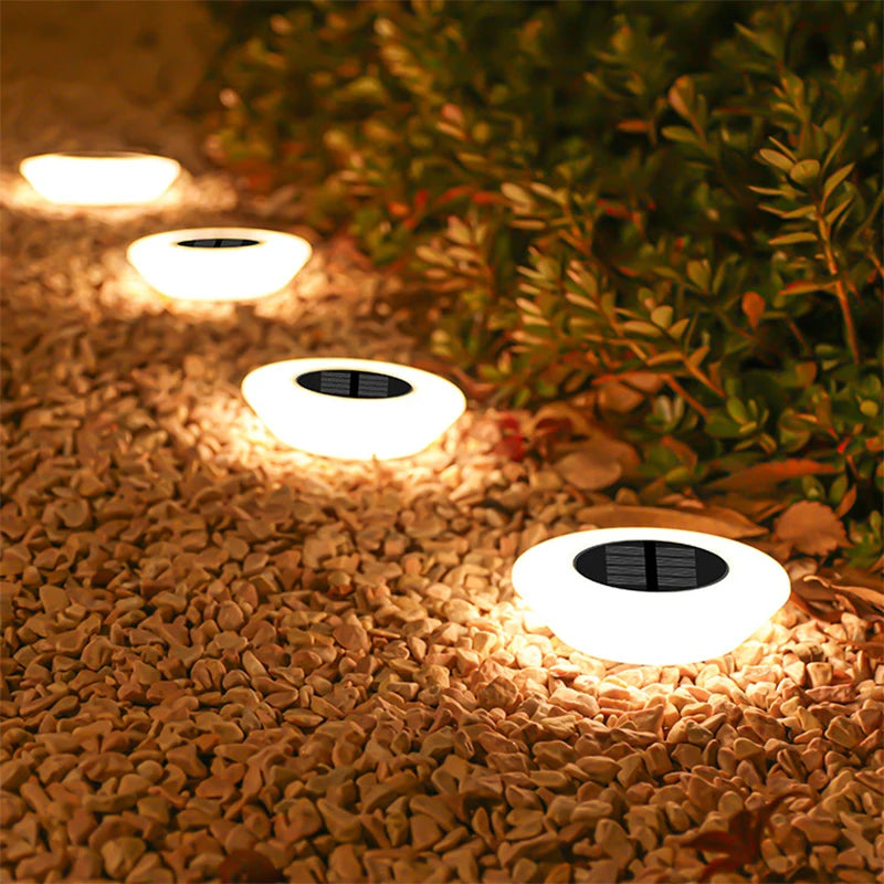 Luminárias solares LED instaladas em caminho de jardim iluminando área externa durante a noite com luz quente e elegante.